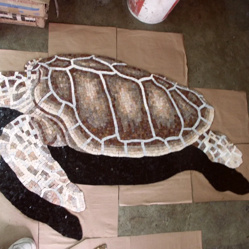 Loggerhead turtle mosaic, hand-cut stone in browns and creams, paper-faced in the studio with its cast shadow worked in mosaic.