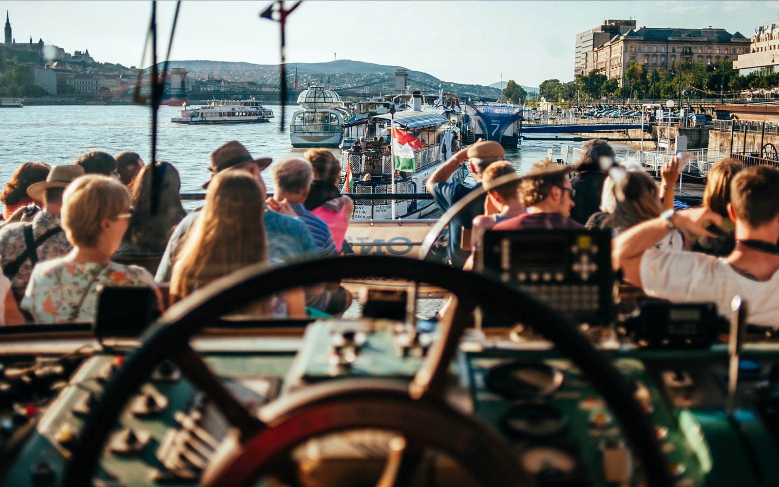 Donau-Flusskreuzfahrt mit sitzenden Touristen, Budapester Skyline im Hintergrund.