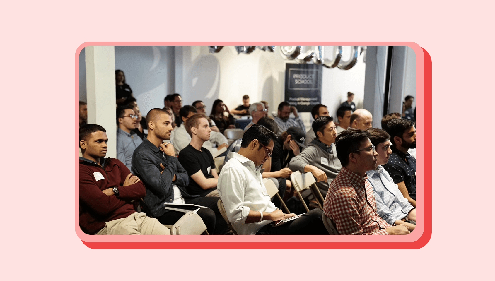 A group of people in a room, actively listening and noting down points.