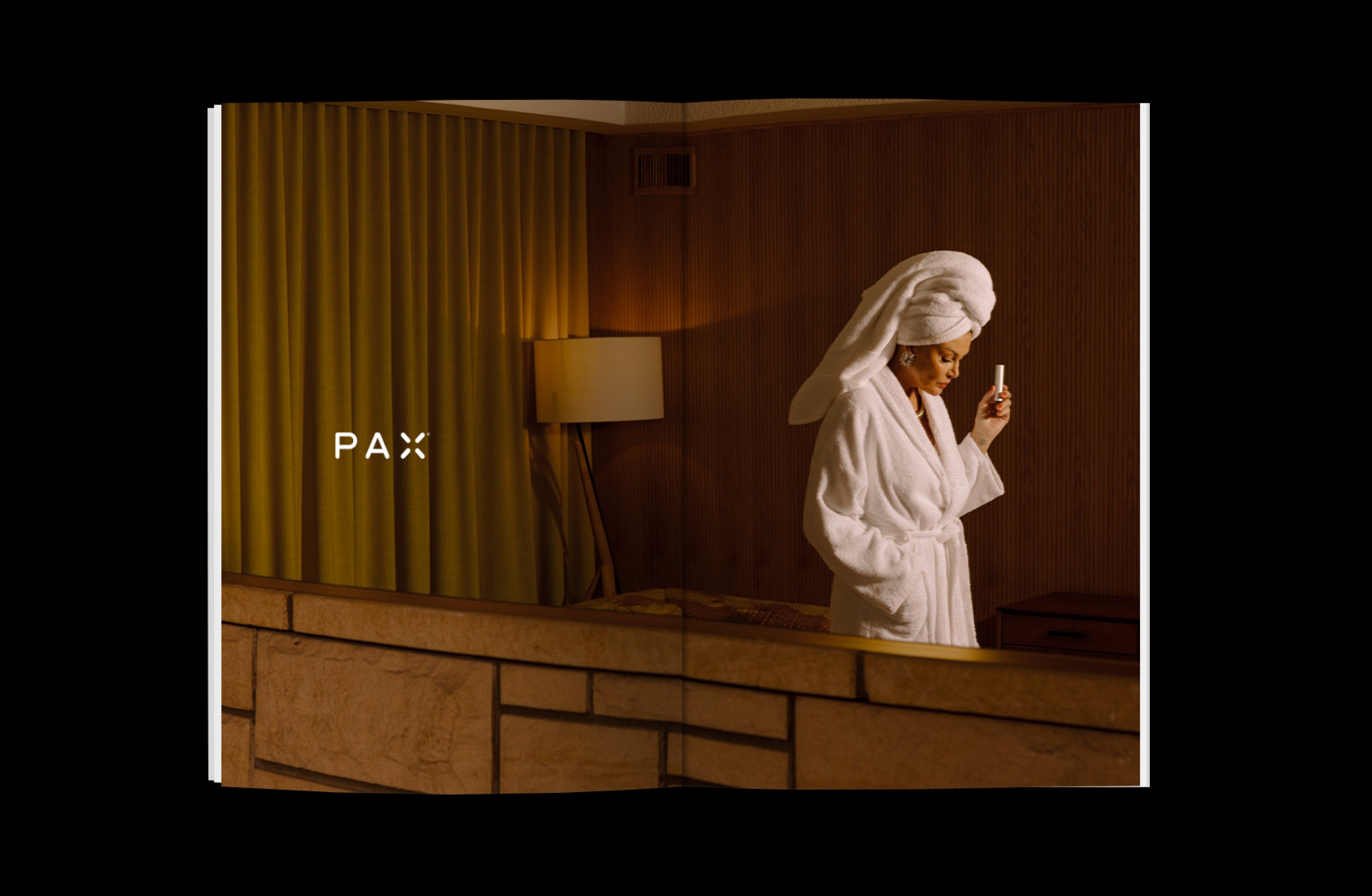 A woman standing in a living room and wearing a bathrobe holds a PAX vaporizer, overlaid with the PAX brand logo.