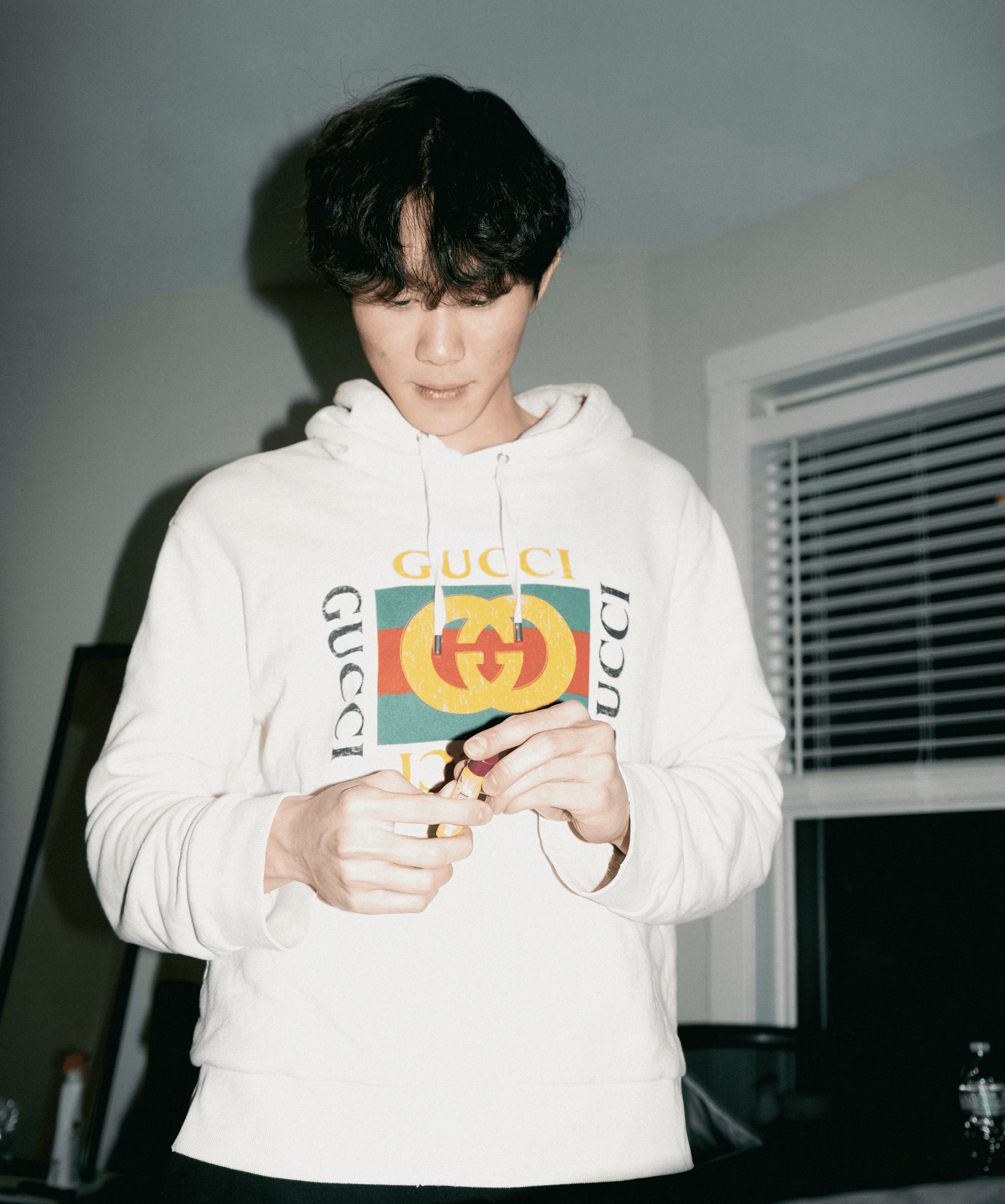 Young man in gucci hoodie holding a small object