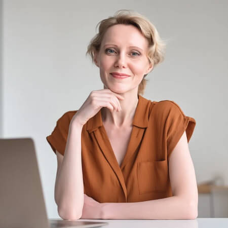 Woman in terracotta shirt presenting client communication and follow-up AI prompt pack for menopause coaches