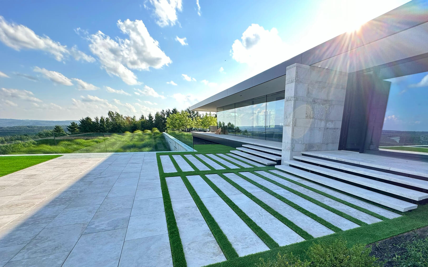 A contemporary house featuring a grassy artificial green lawn by AGL Grass and elegant stone steps leading to the entrance, showcasing modern architecture.
