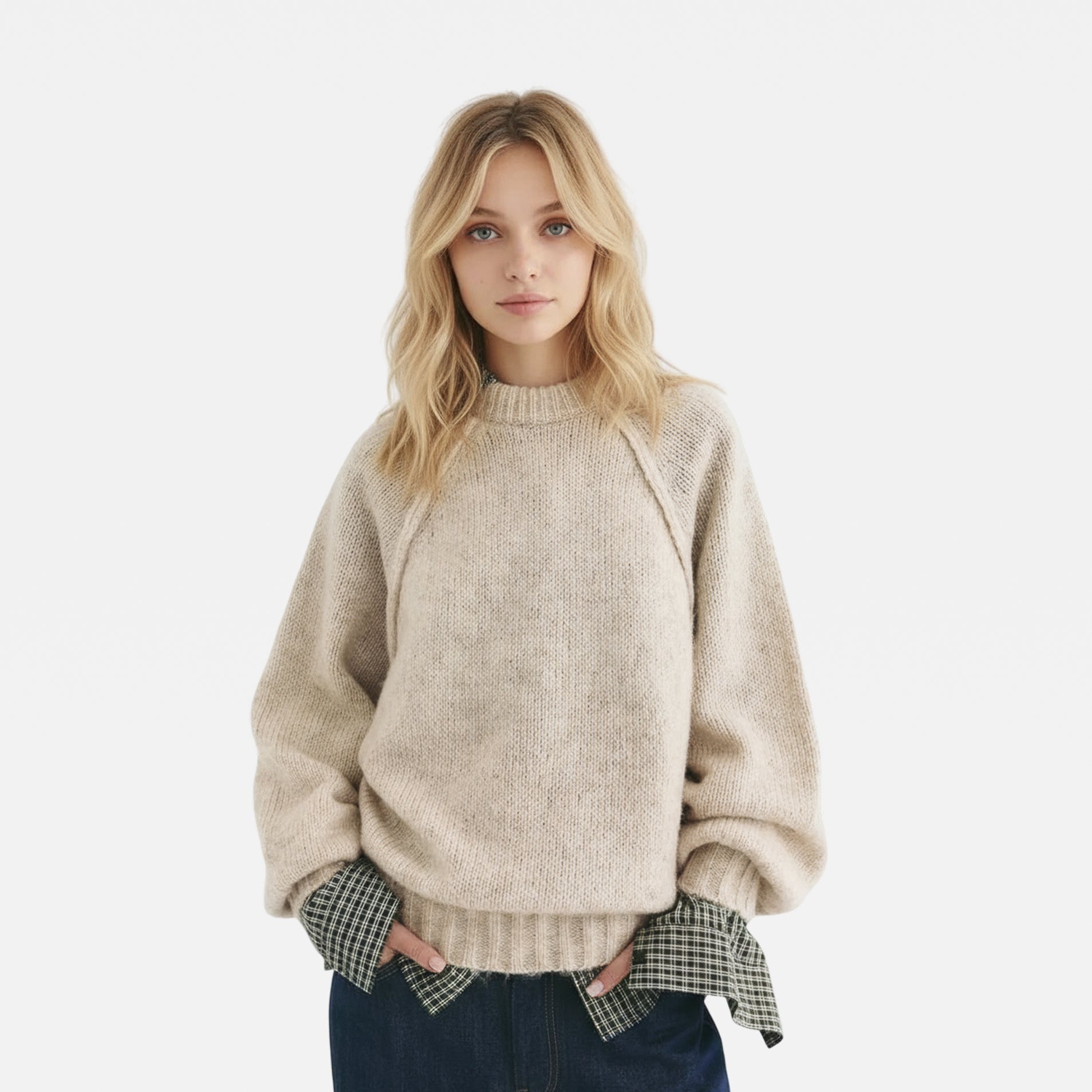 Woman wearing a beige sweater over a plaid shirt on a white background