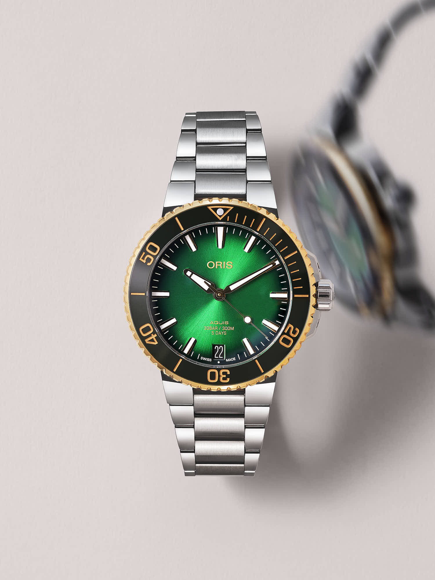 Luxury Oris Aquis watch with green dial and stainless steel bracelet.
