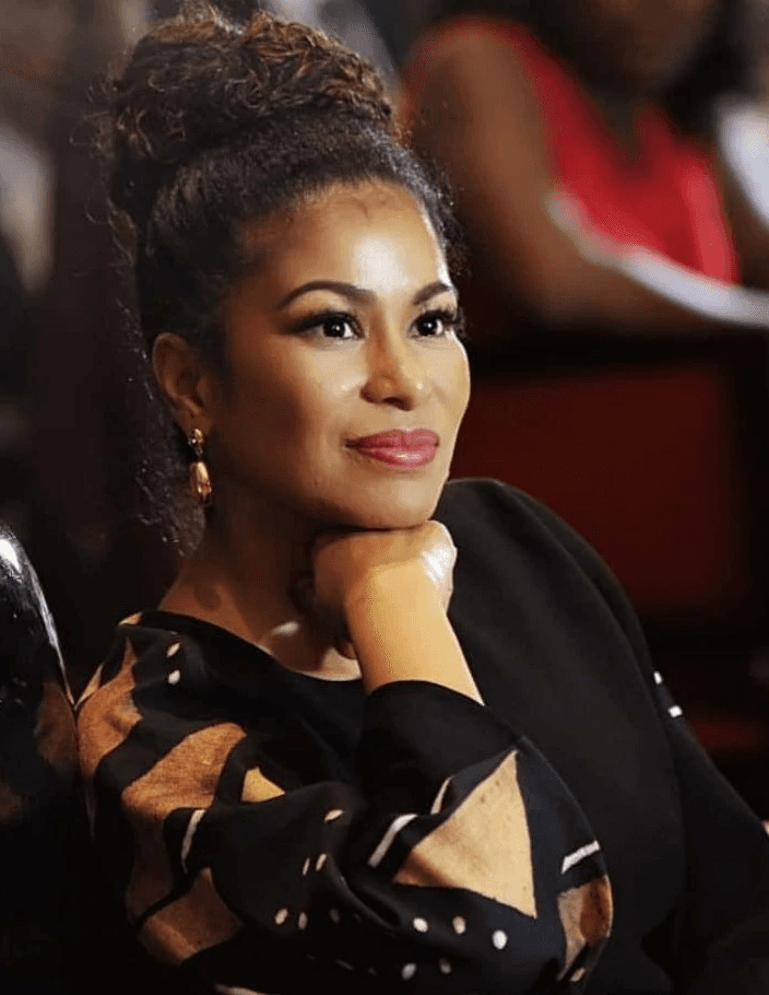 A young man with dark hair smiles at the camera, set against a modern indoor background.