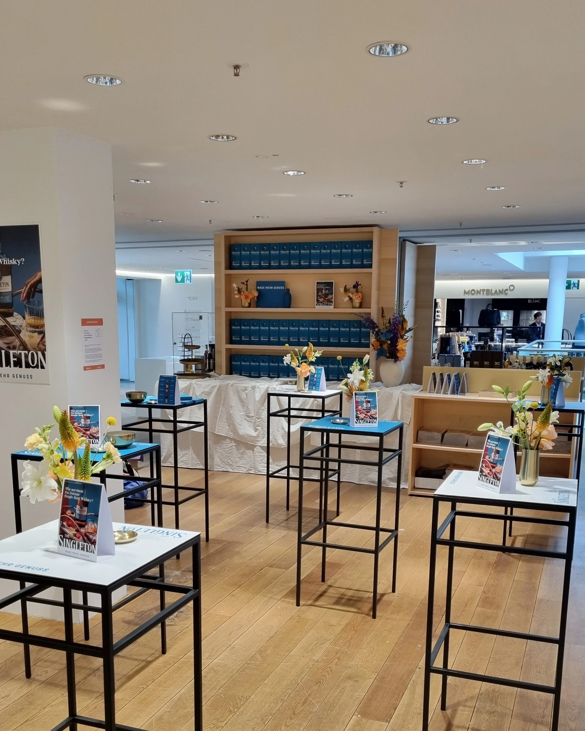 Singleton pop-up in the department store with black high tables, flowers and packaging shelf.