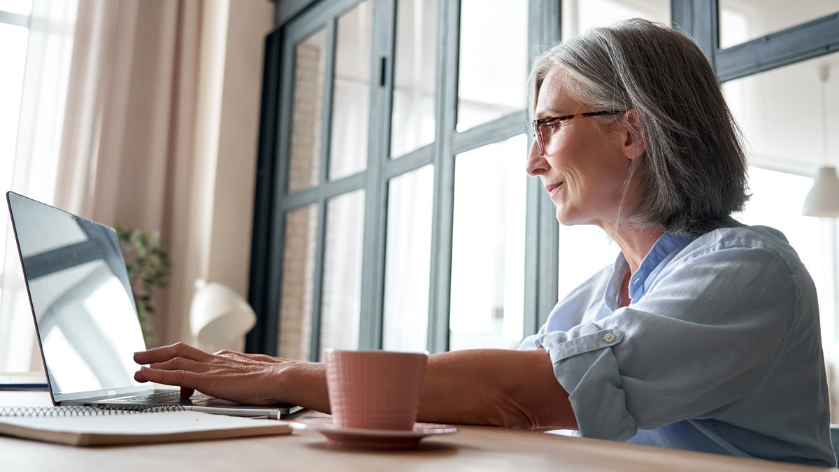 A woman working sitting at her desk and typing on a computer 