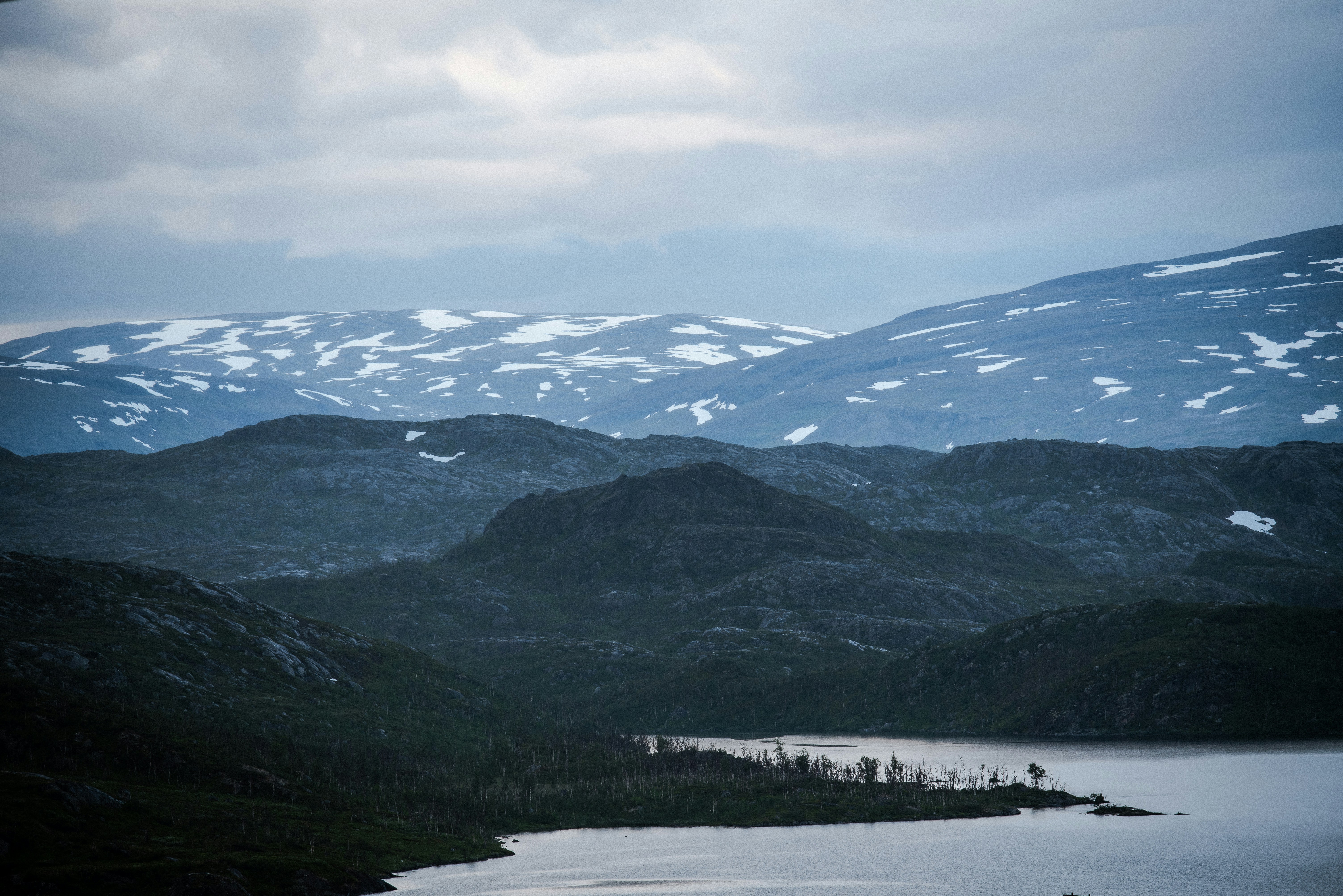 snow covered mountain near lake under white clouds during daytime