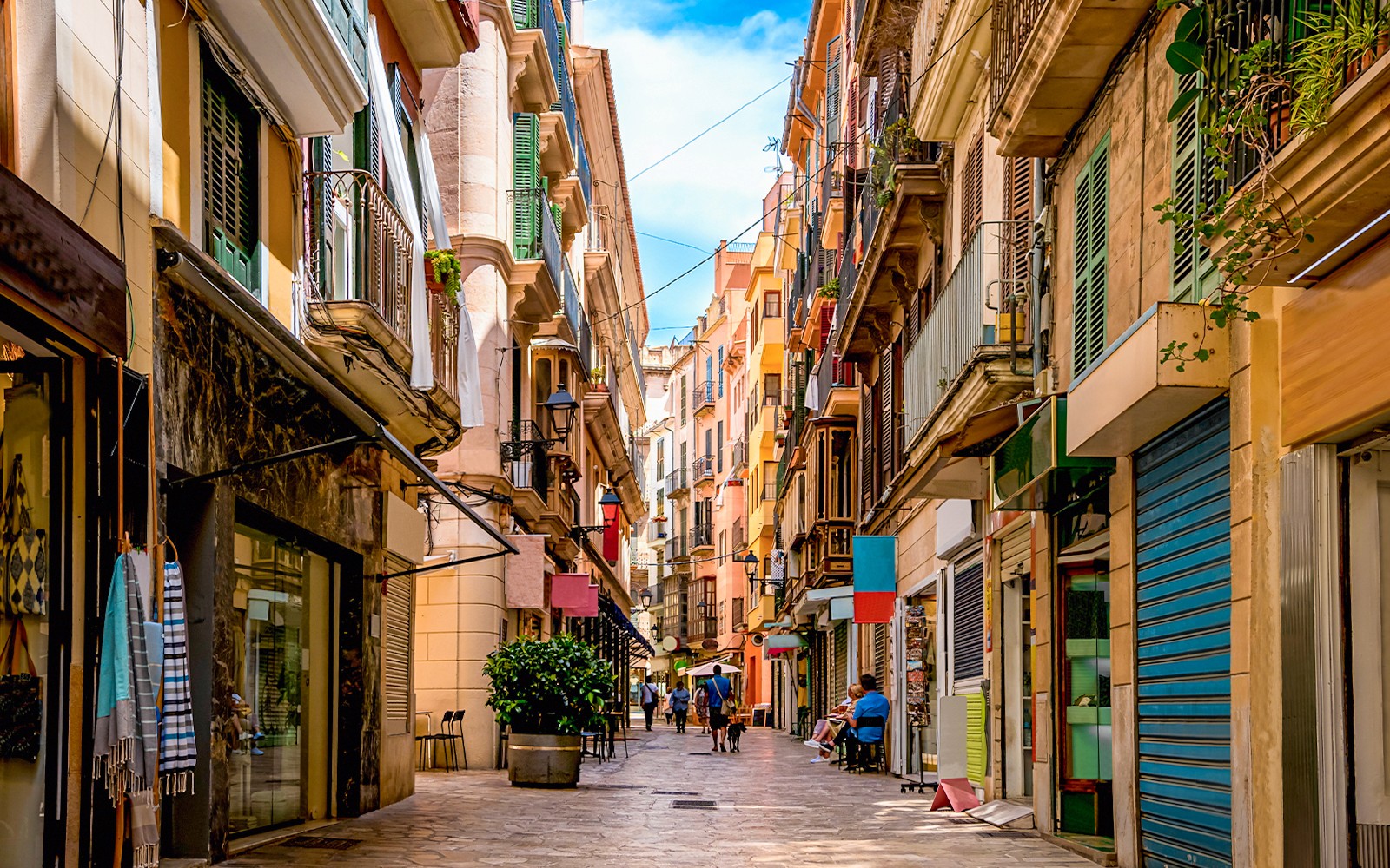 Calle estrecha en el distrito comercial de Palma de Mallorca, con edificios coloridos y personas caminando.