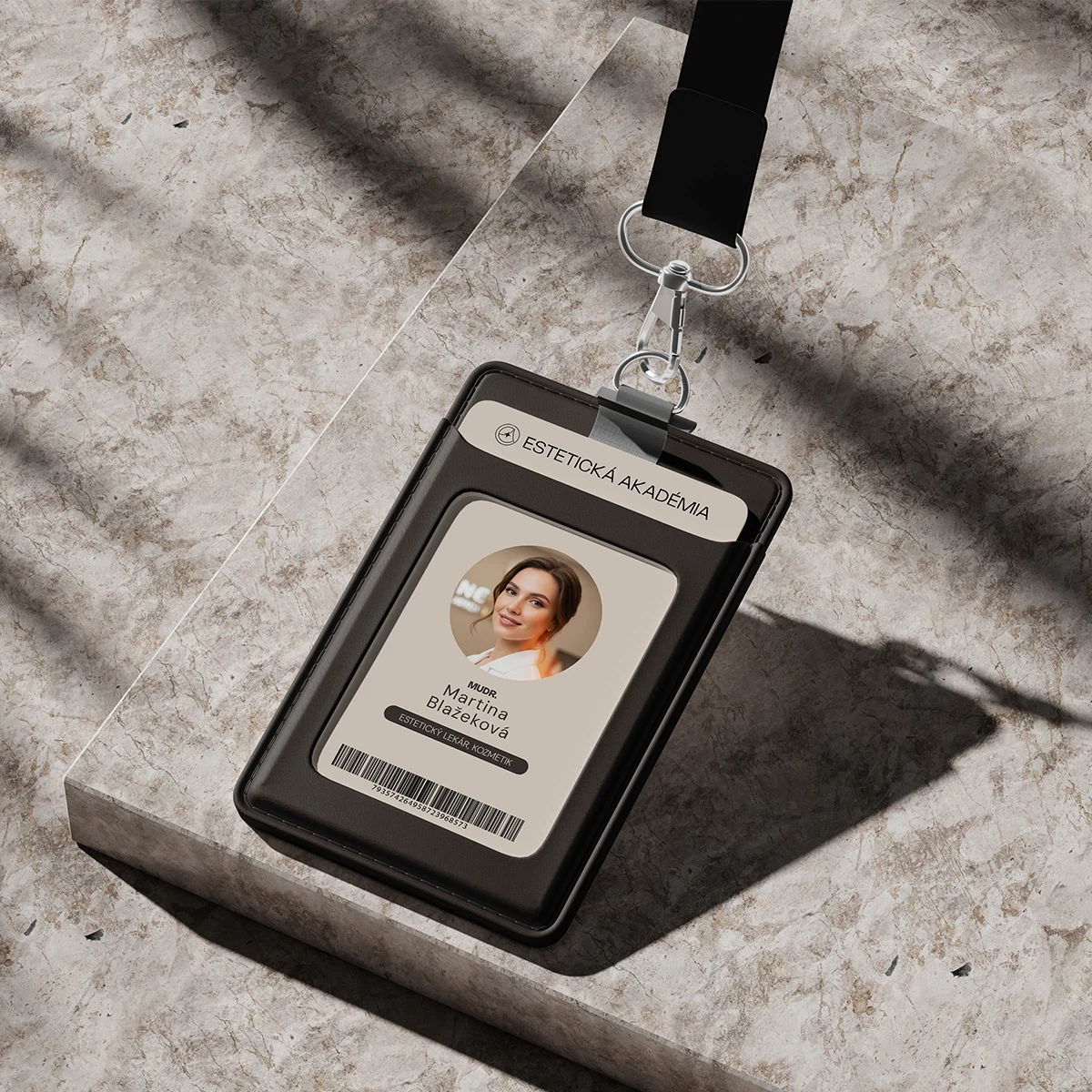 An ID badge hangs from a black lanyard, resting on a textured surface with a soft shadow.