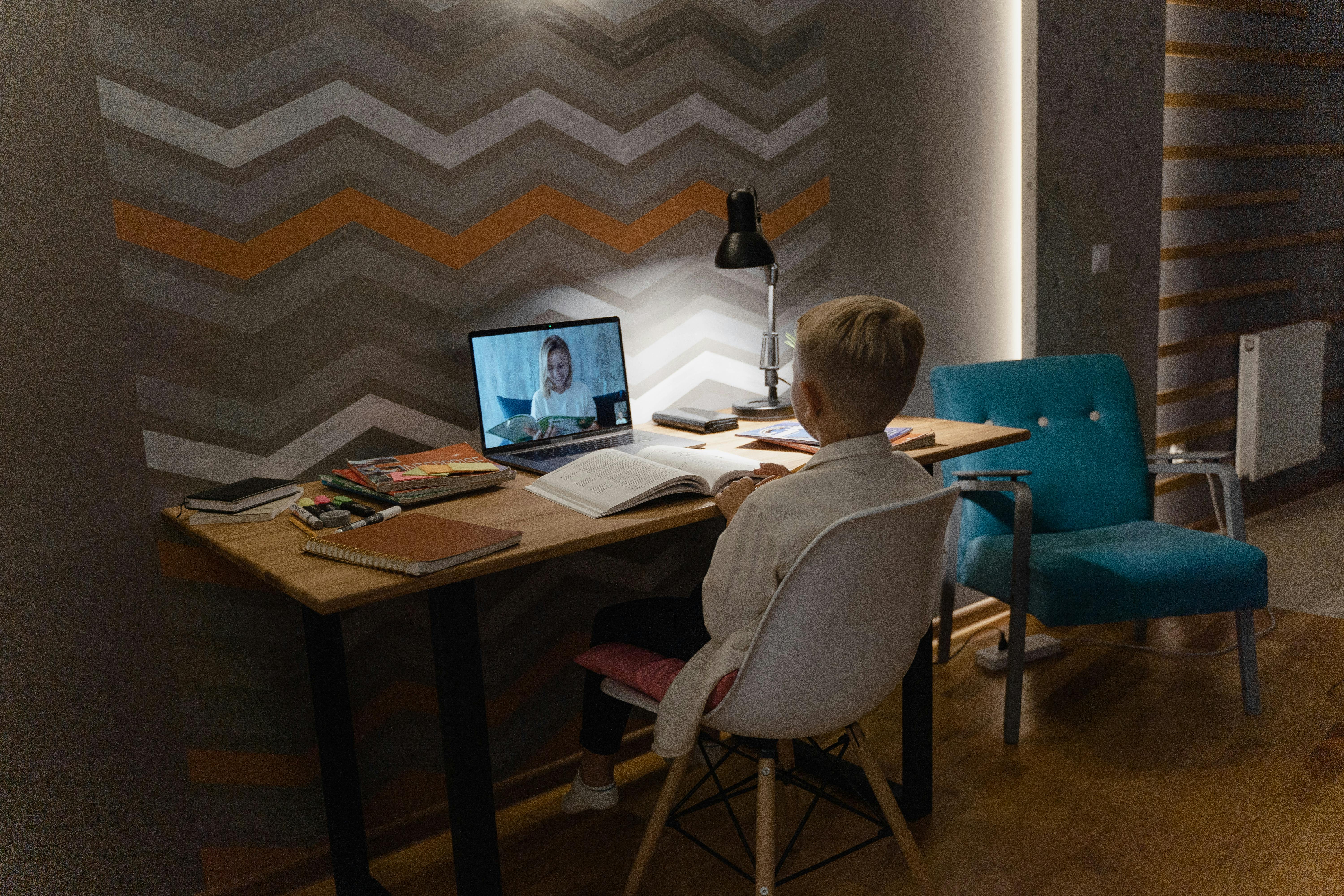 A child in a dark room on a laptop preparing for school work