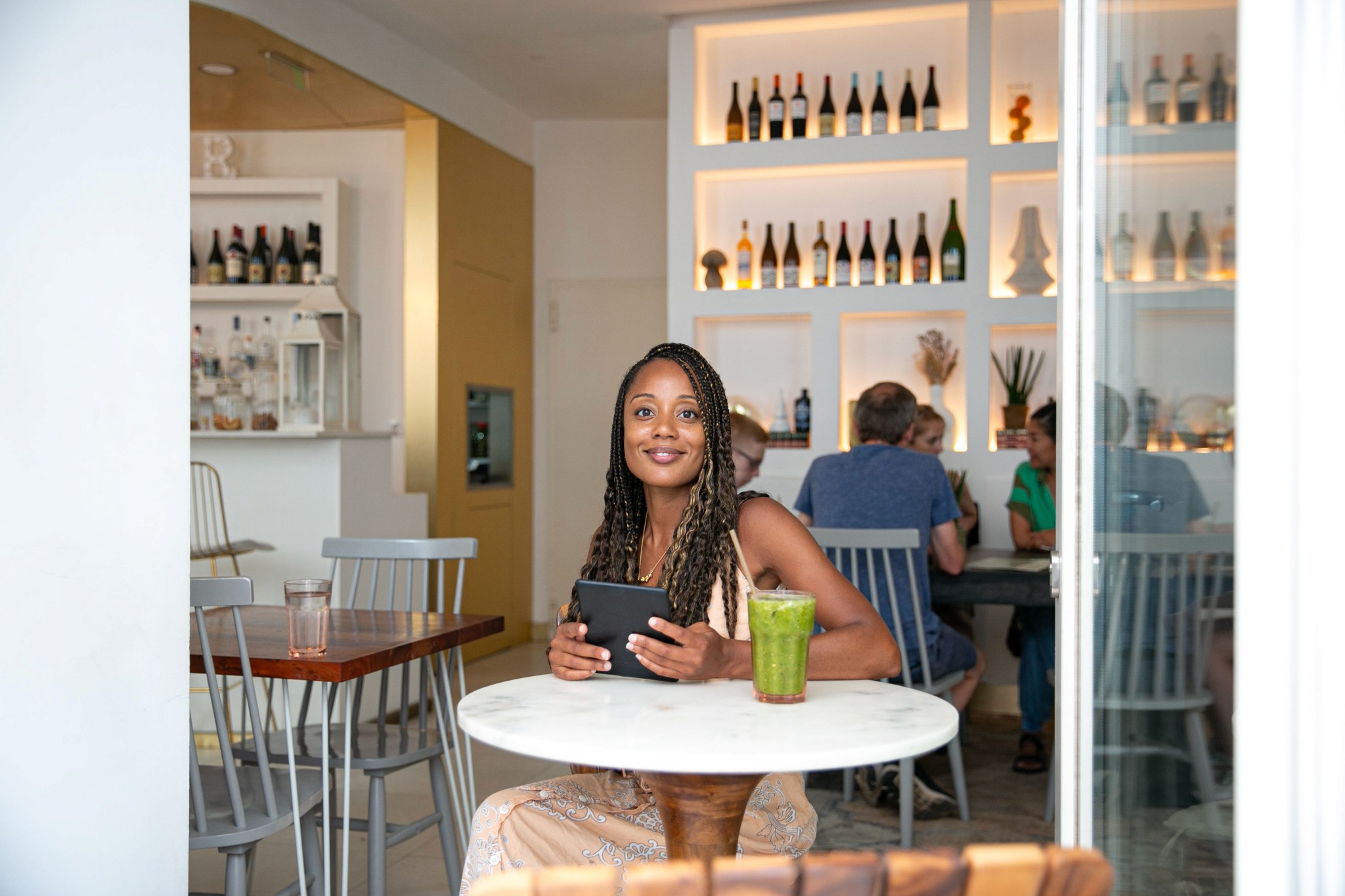 Rita Batalha sitting in a cafe with a Kindle in her hands and a green juice