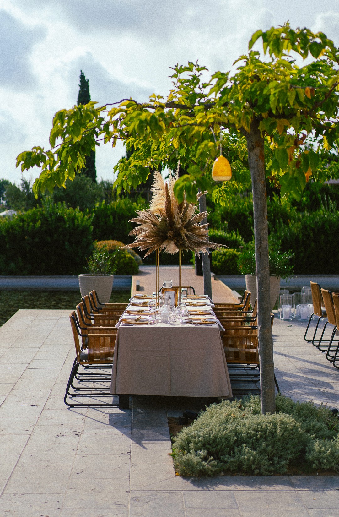 Luxury outdoor wedding reception setup with long wooden tables and lush white floral runners in a Greek estate venue