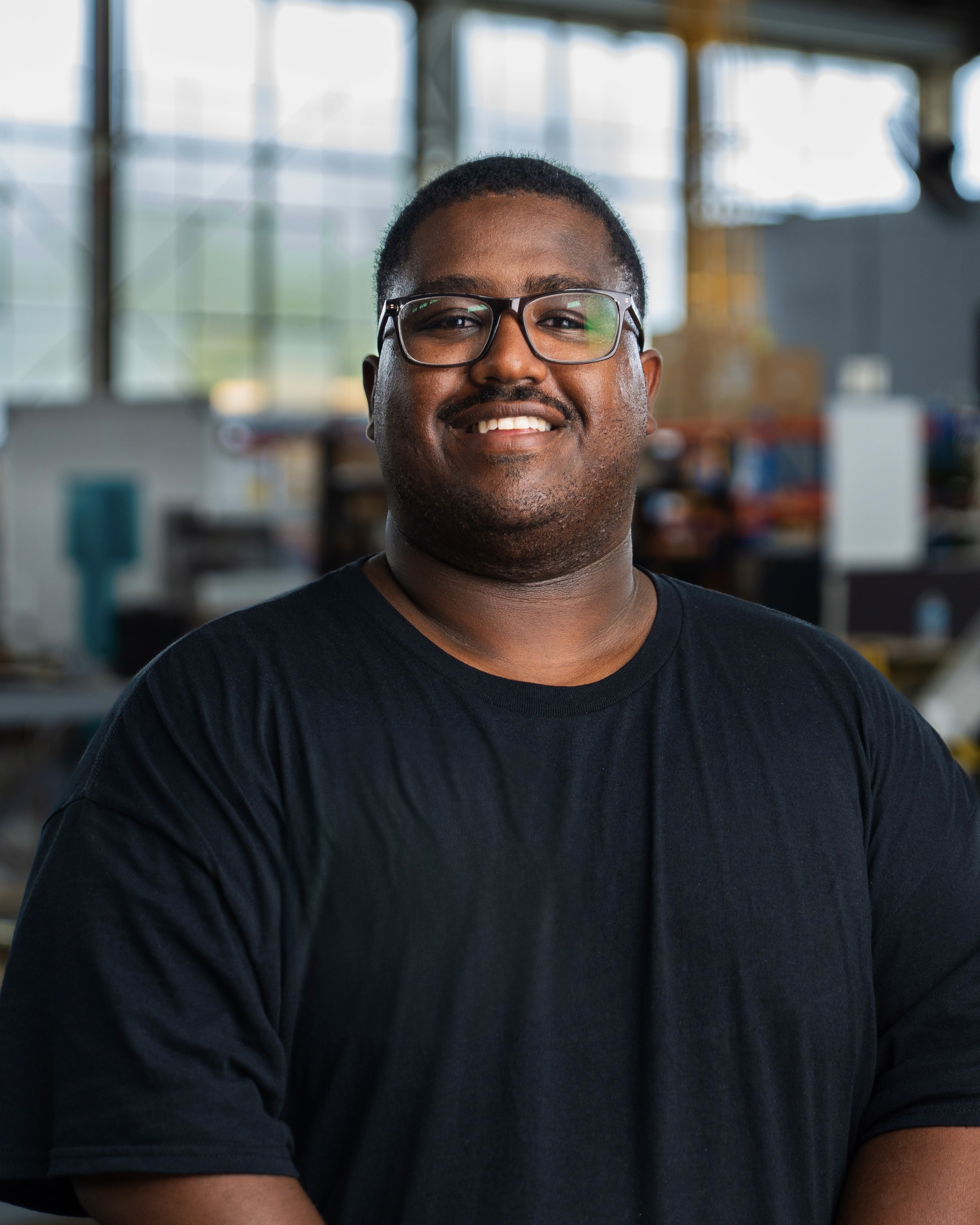 Silhouette of a camera operator filming on a professional set, surrounded by bright studio lights. The scene conveys focus and creative energy.