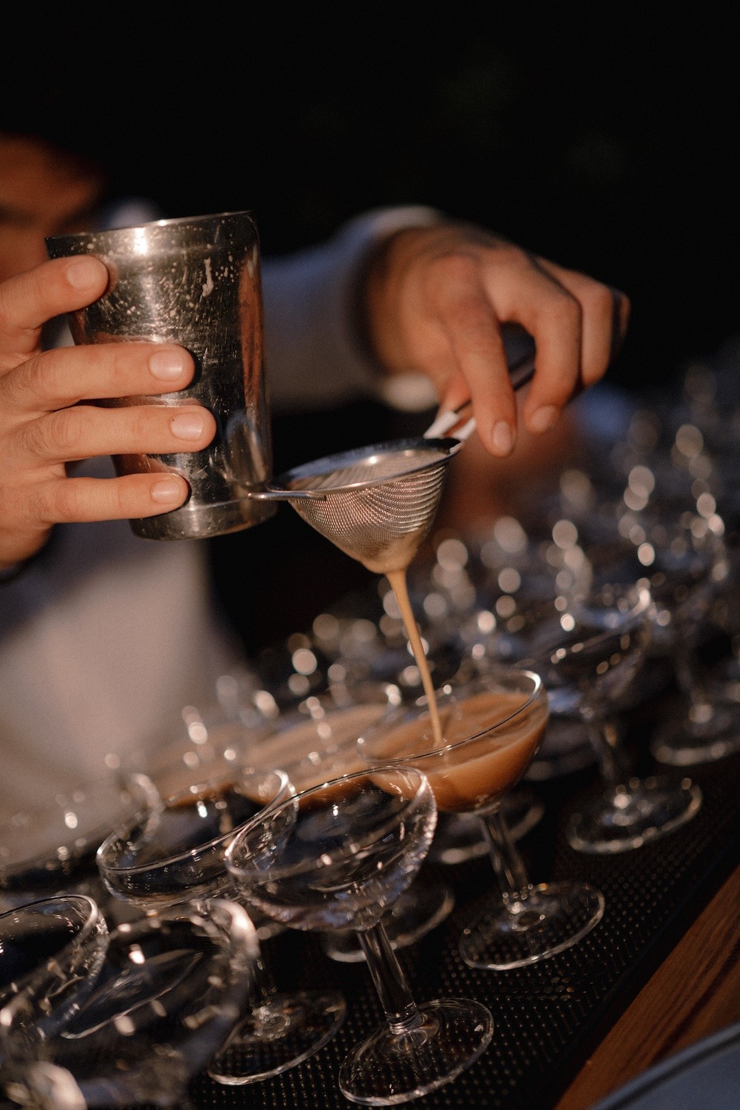 Bartender pouring espresso martinis into coupe glasses during wedding cocktail service in Ibiza.