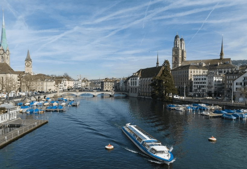 Vue panoramique de Zurich avec la rivière Limmat, mettant en valeur la mobilité urbaine et les options de transport dans la ville, y compris les bateaux et les solutions de voyage durables en Suisse.