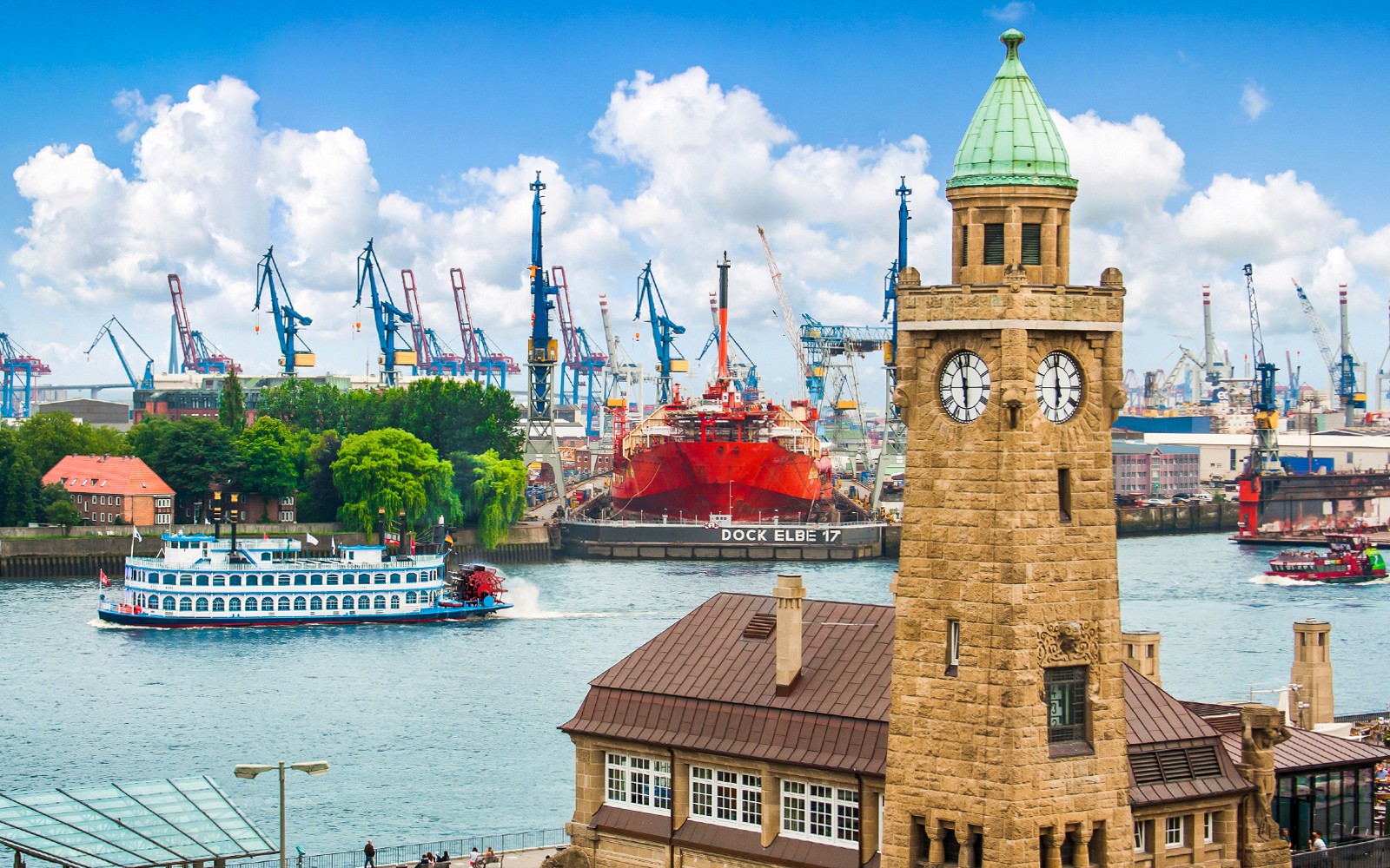 Uhrenturm und Schiffe im Hamburger Hafen mit Kränen im Hintergrund.