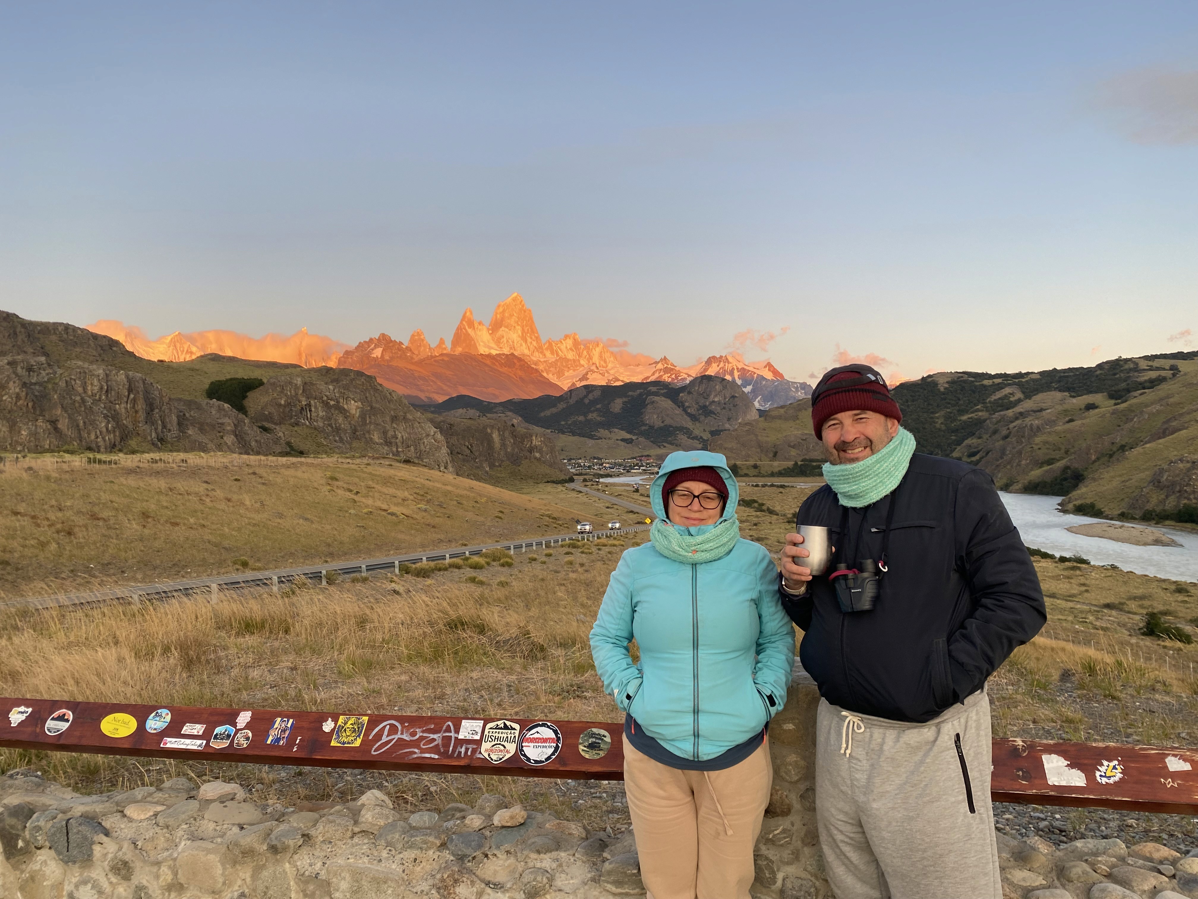 Mujer sentada sobre un tronco frente a una cascada doble en un bosque frondoso de Argentina.