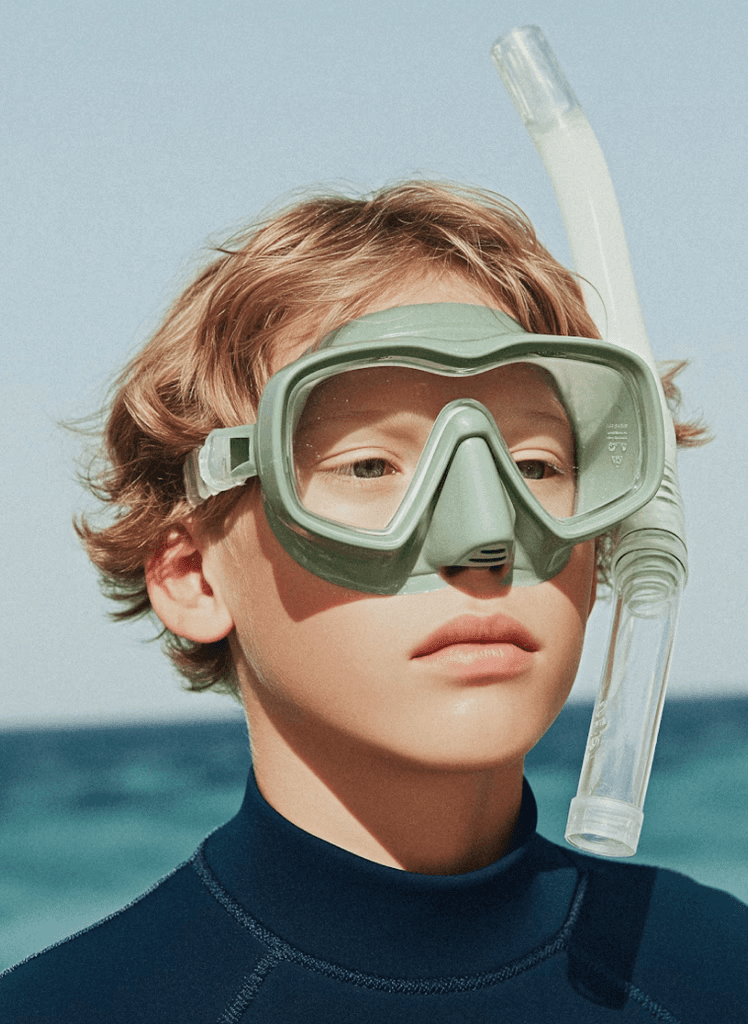 Woman in sun hat and white outfit sitting by poolside with clear water