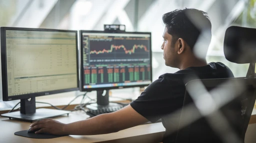 Person analyzing financial data and stock market charts on coinswitch on dual computer monitors in an office setting.