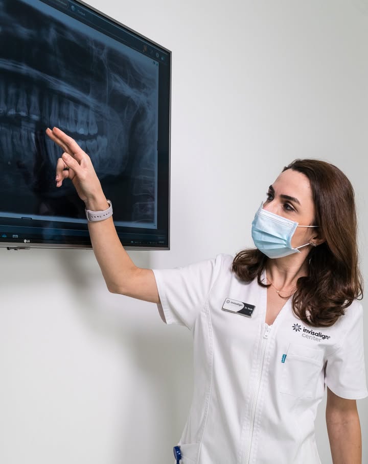 صورة توضح أحد خطوات علاج انقطاع النفس الانسدادي النومي بها طبيبة أسنان تستعرض صورة أشعة لفم المريض و تناقش معه خيارات العلاج والنتائج المتوقعة.