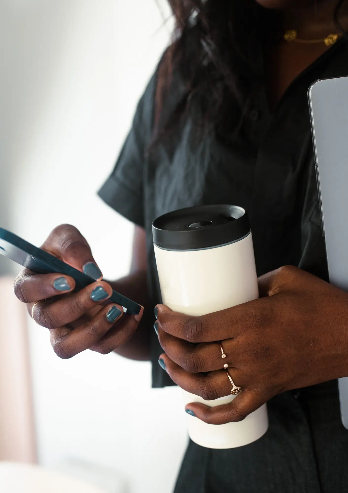 Une personne avec un téléphone dans une main et une gourde dans l'autre.