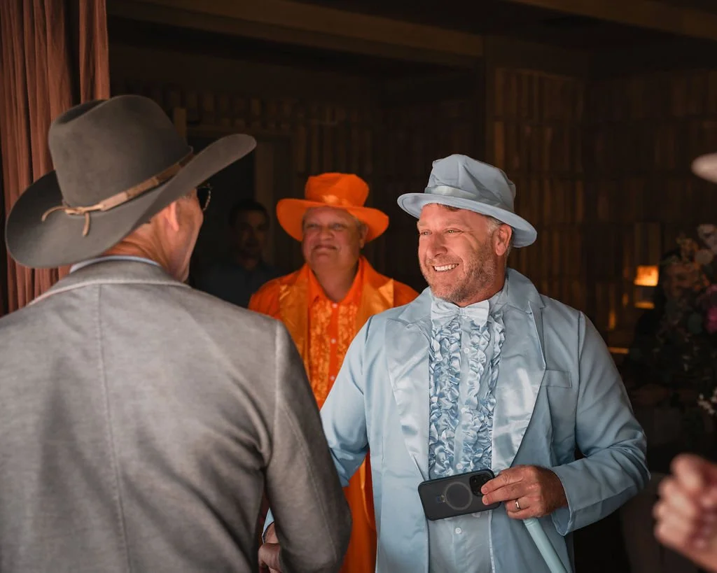 Wedding guests in colorful hats talking indoors