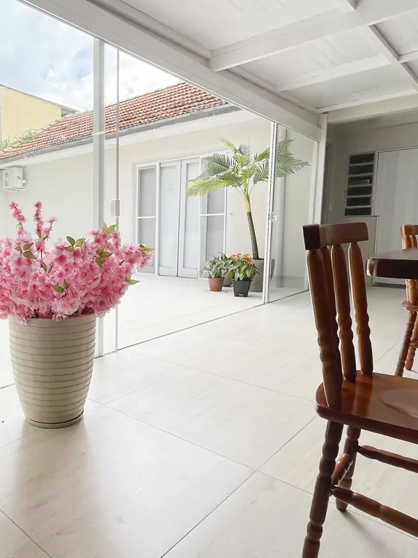 Idosos em área de convivência externa com jardim arborizado e bancos de descanso.