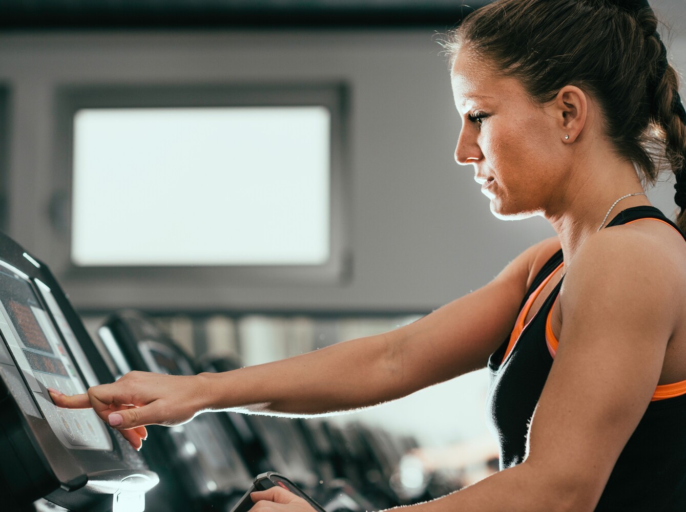 woman choosing settings for the best way to lose weight on treadmill at the gym