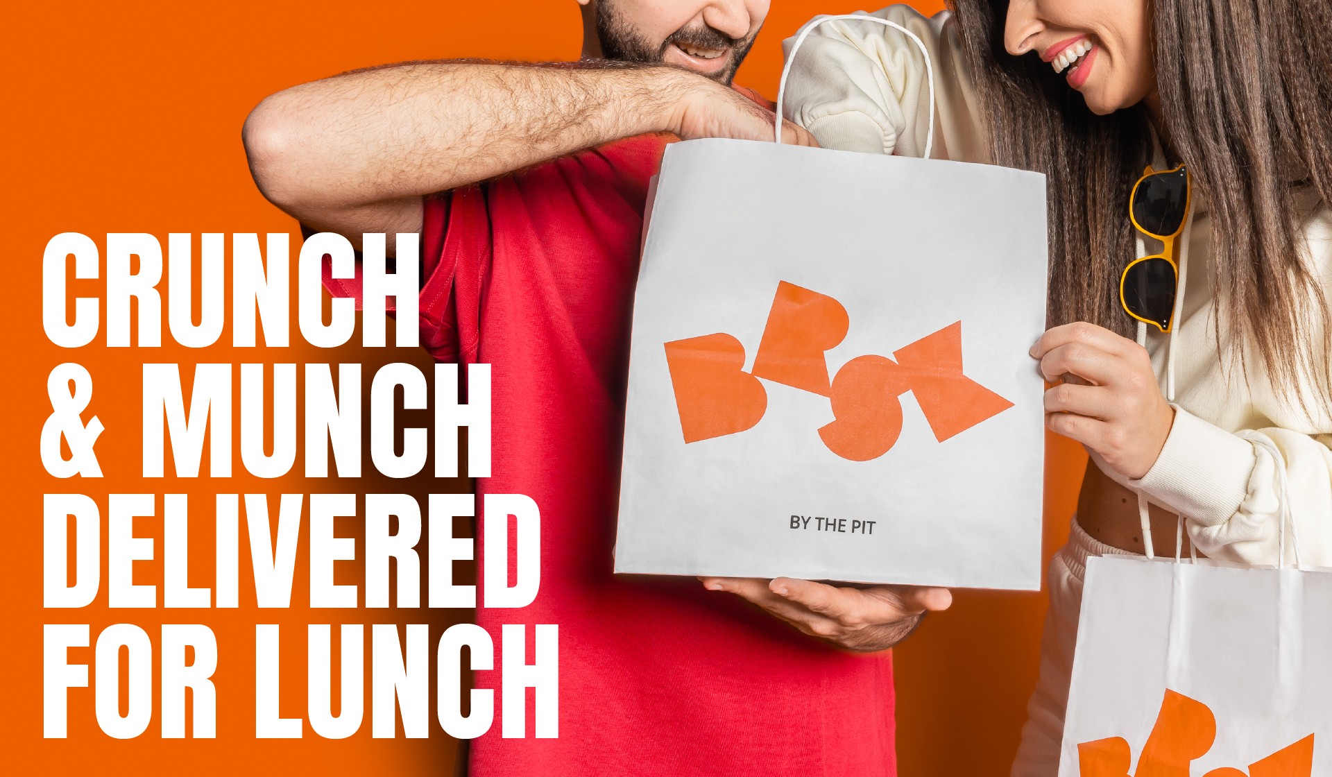 BRSK BY THE PIT, DUBAI, UAE, FASTFOOD CHAIN, BRSK LOGO, GREEN AND ORANGE, COUPLE HOLDING DELIVERY PAPER BAGS,CRUNCH MUNCH DELIVERED FOR LUNCH