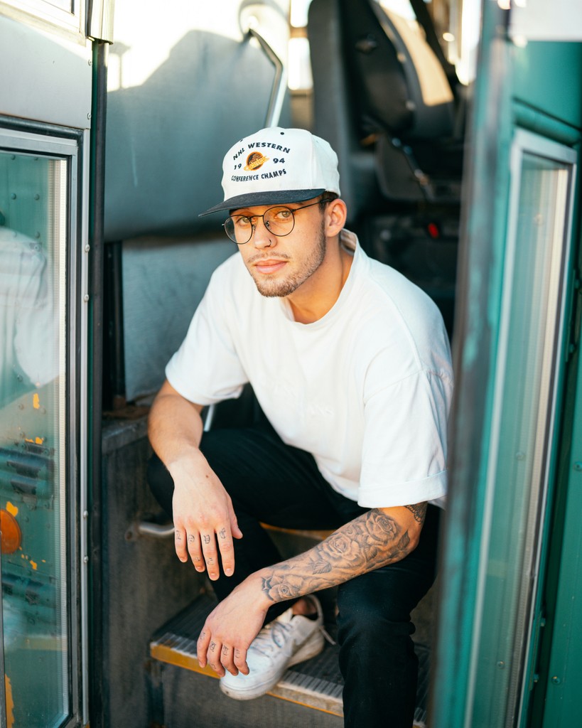 A man with a tattoo and cap in a vehicle doorway, embodying a distinct urban **user persona**.