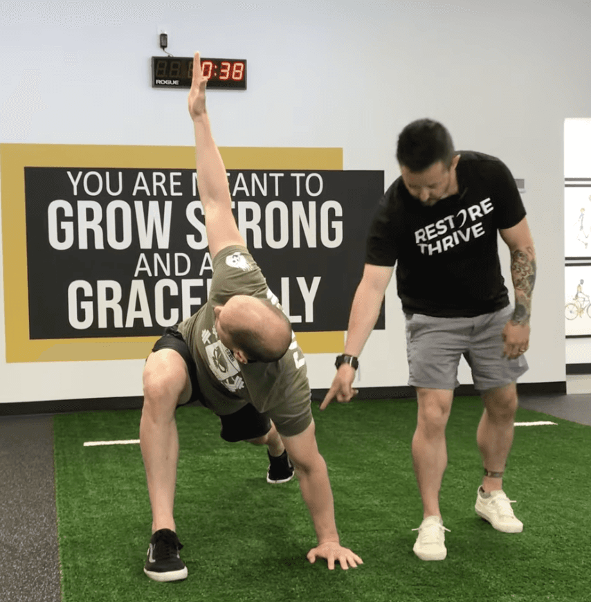 An athletic trainer coaching an athlete in a gym space.