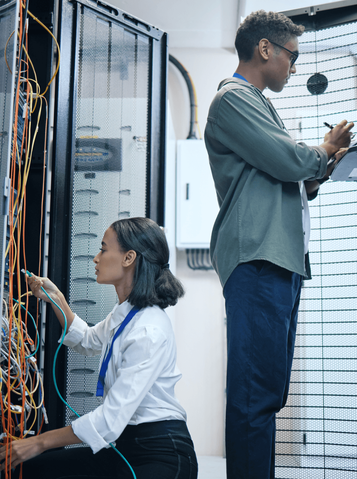 A man and a woman working in a server room 