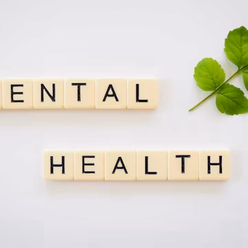 the word mental health spelled with scrabbles next to a green leaf