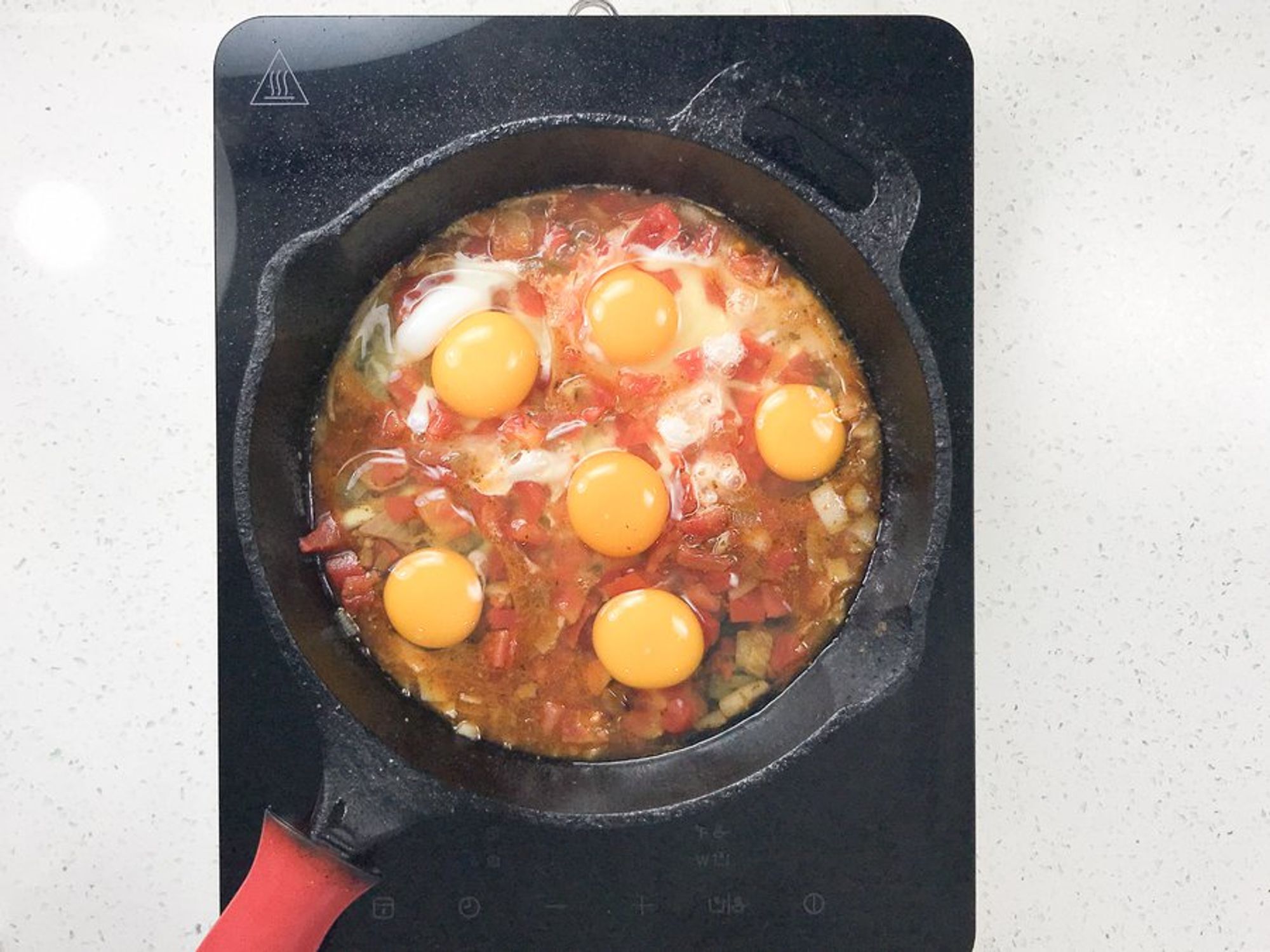 ingredients for mexican shakshuka being cooked in a bottomed skillet