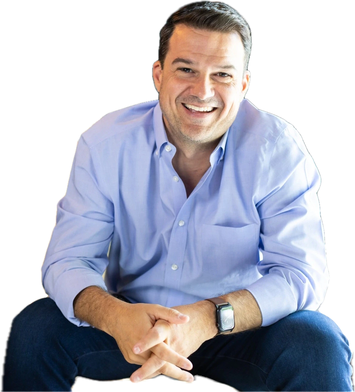 Lance Pendleton sitting forward with his hands clasped, laughing, looking at the camera.