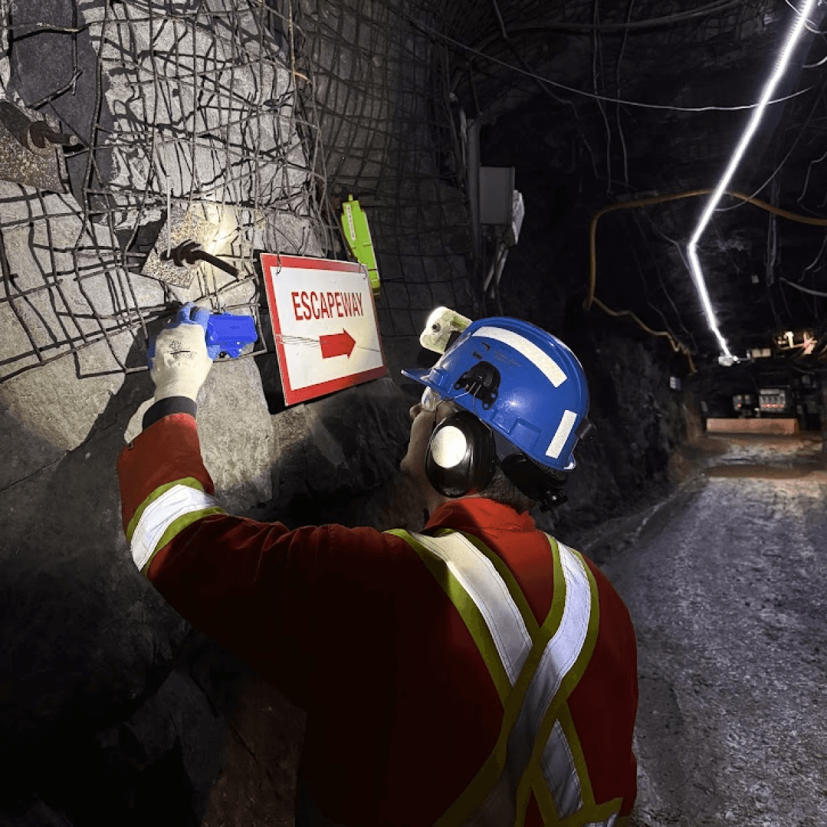Installer adjusting a Dorado anchor near an escapeway sign in a NORCAT drift