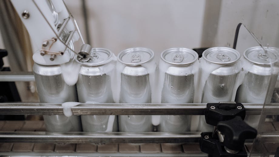 Close-up of aluminum cans on an assembly line in a modern brewery showing automation and machinery at work.