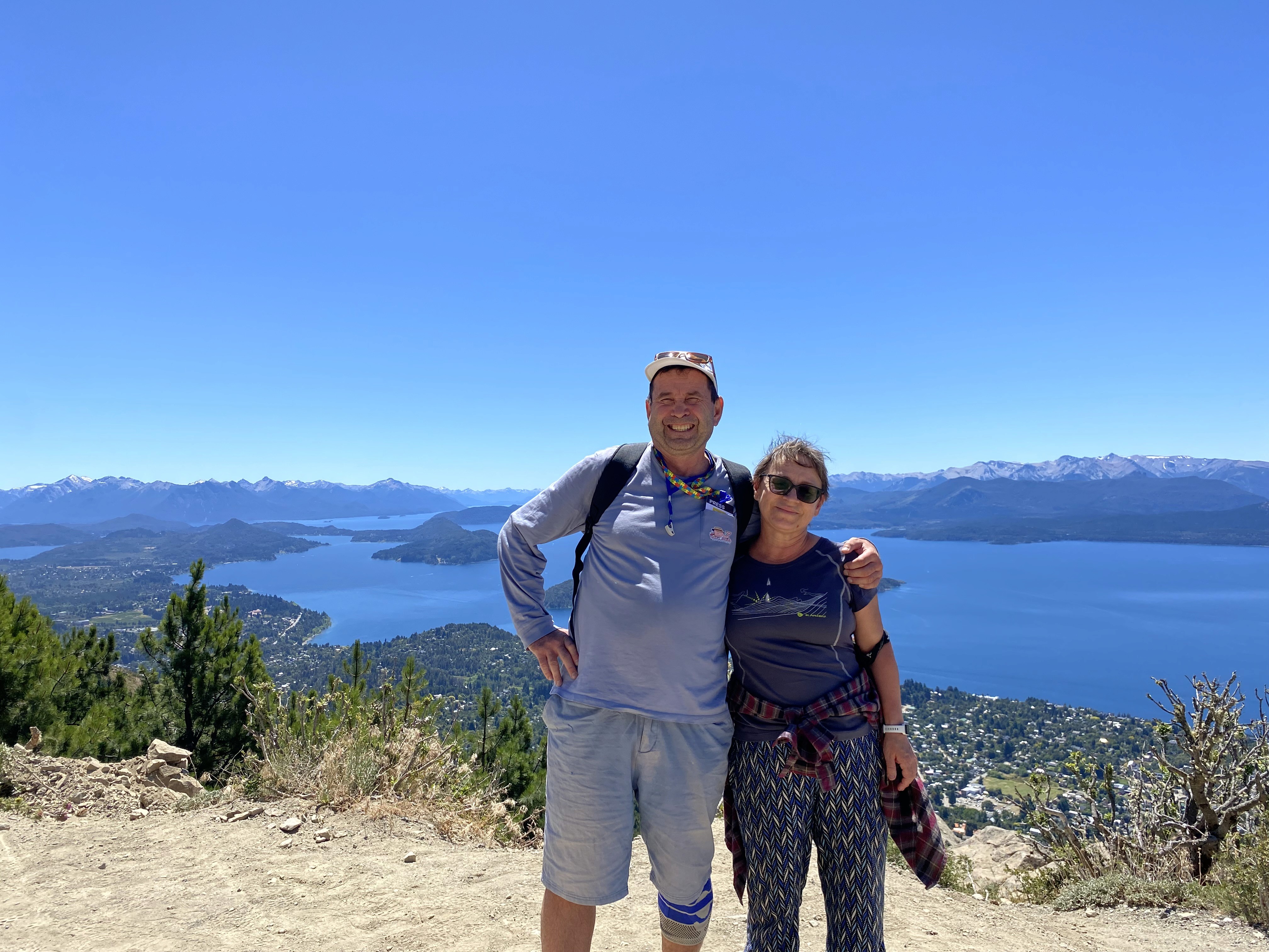 Mujer sentada sobre un tronco frente a una cascada doble en un bosque frondoso de Argentina.