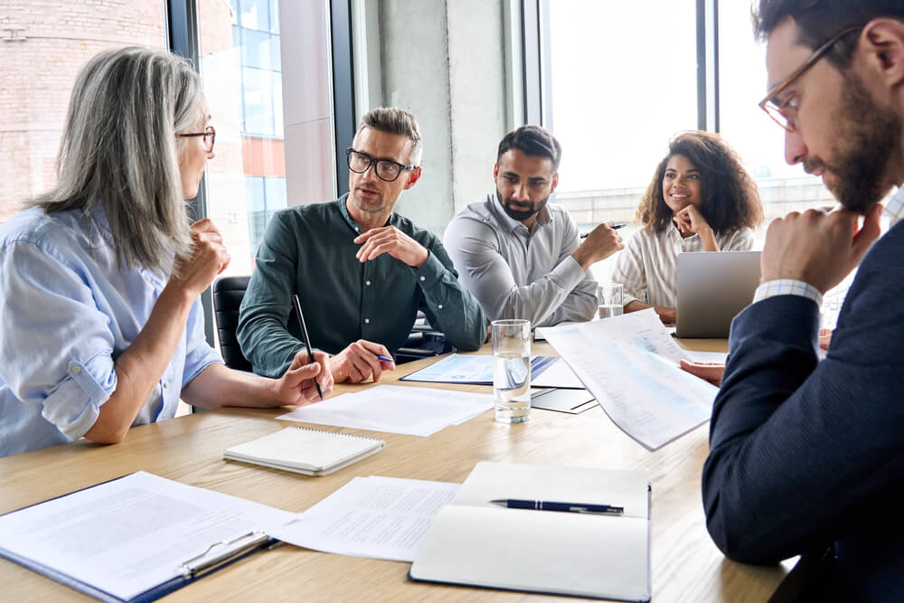 Group of five business people at desk with papers