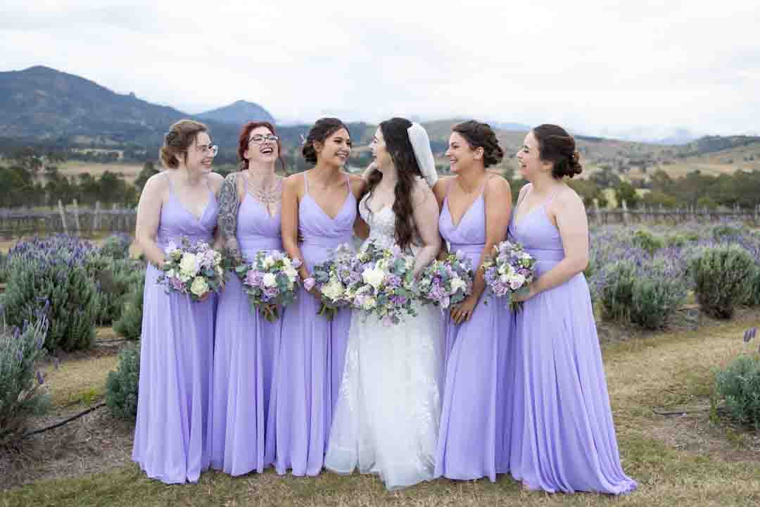 Bridal party smiling at each other in front of lavender field