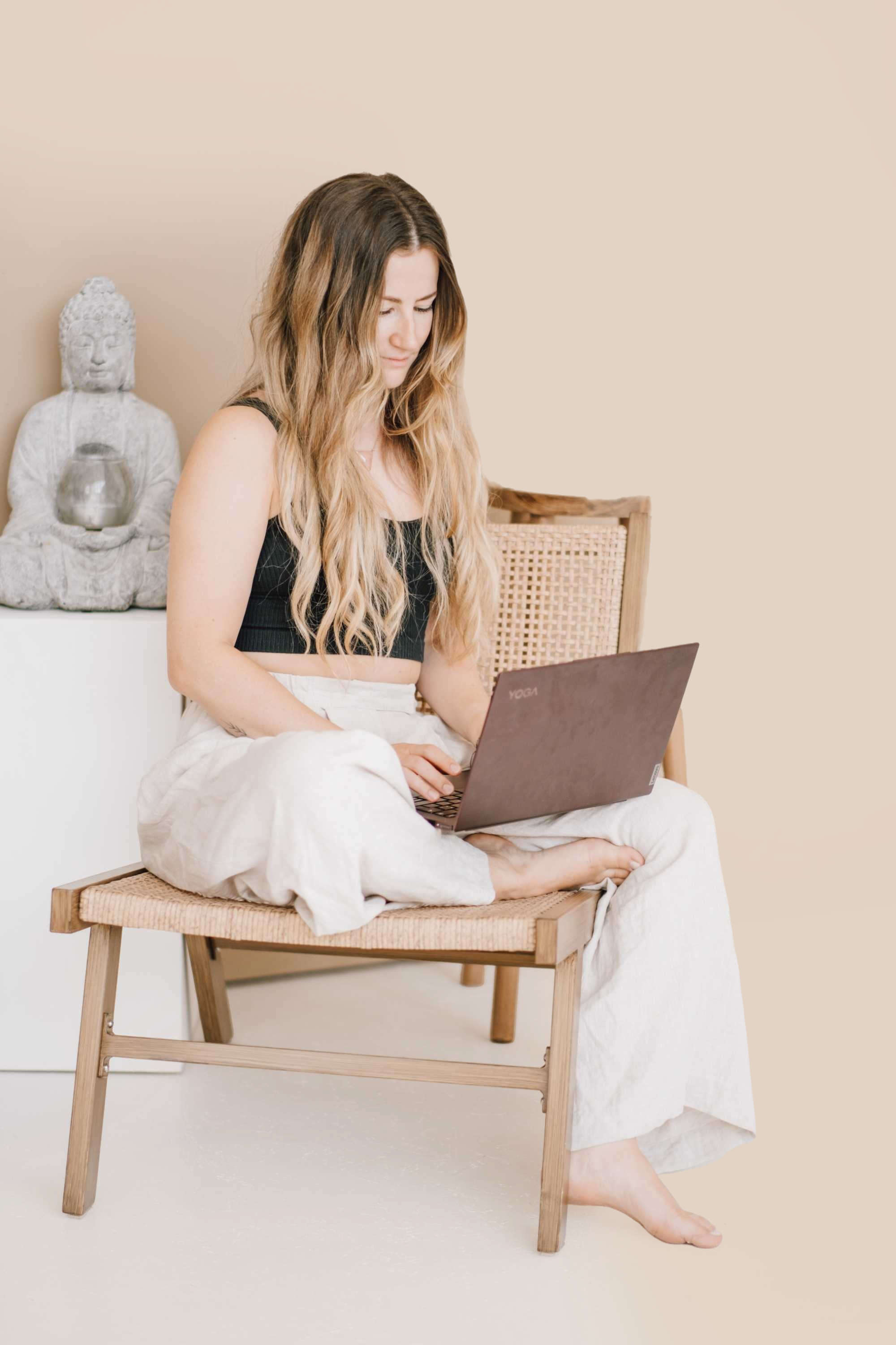 Antonia sitzt auf Stuhl und tippt an Laptop