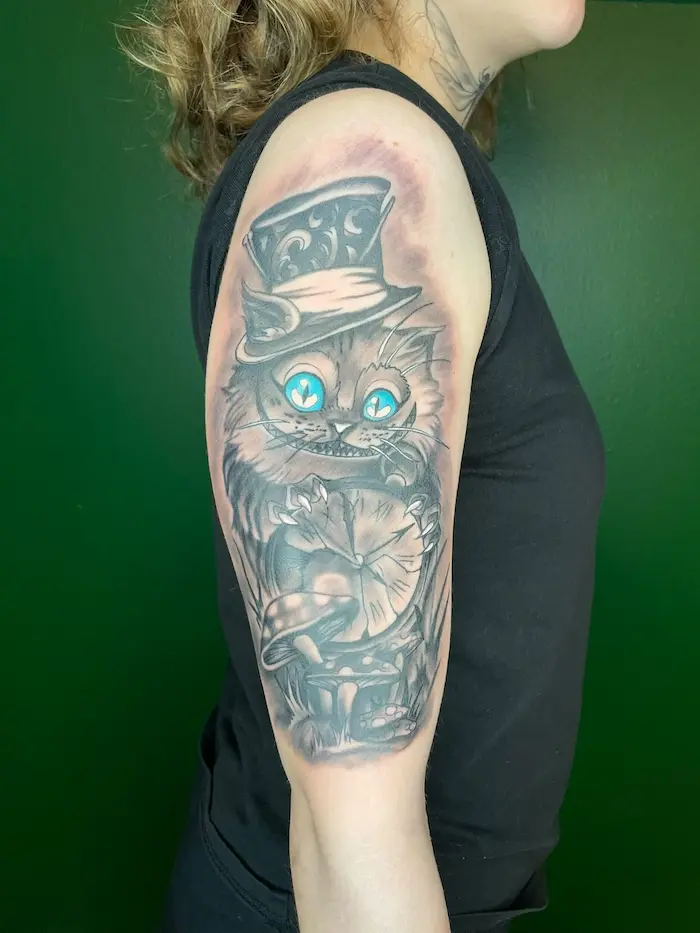 Black and grey armtatuering med Cheshirekatten i hög hatt, High Heels Tattoo Västervik