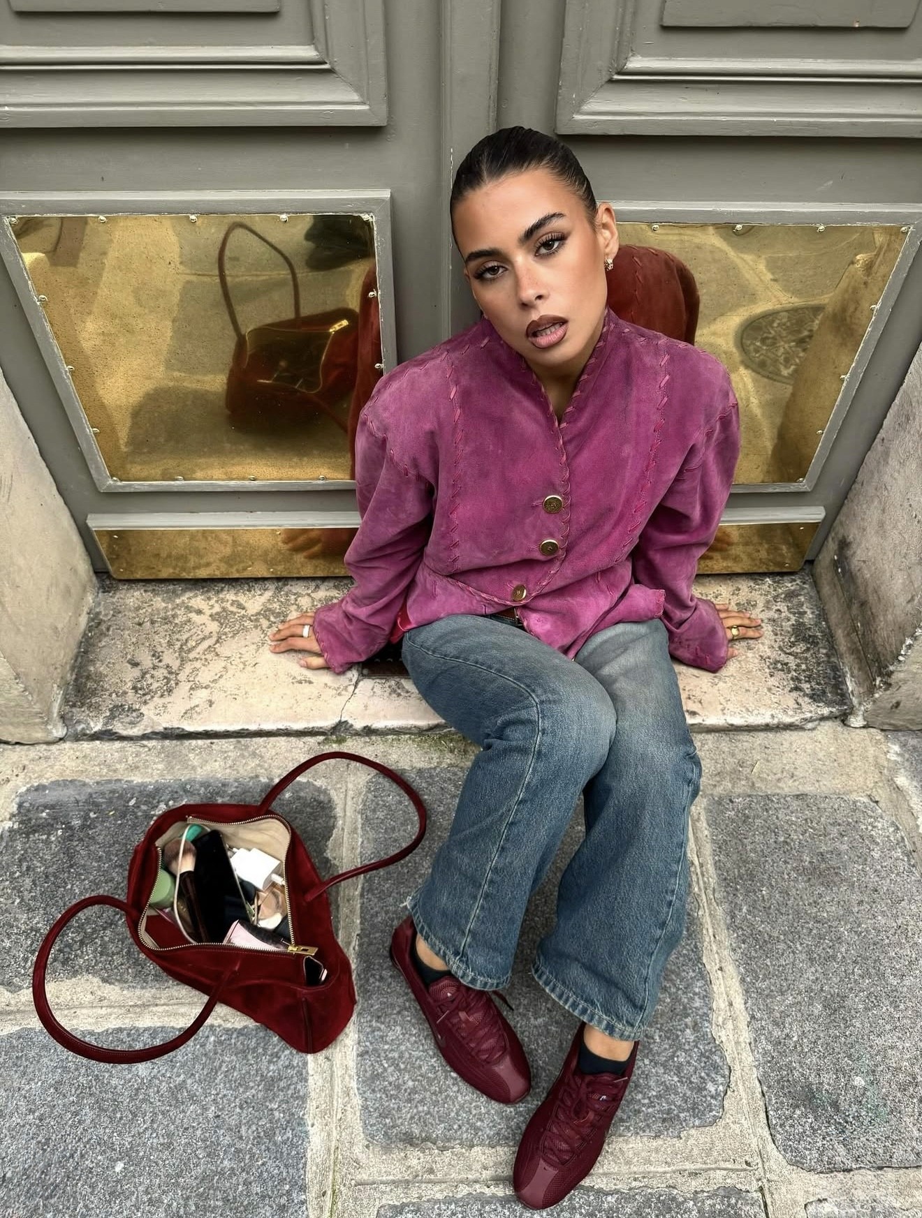 Jade gattoni devant une porte avec des panneaux dorés