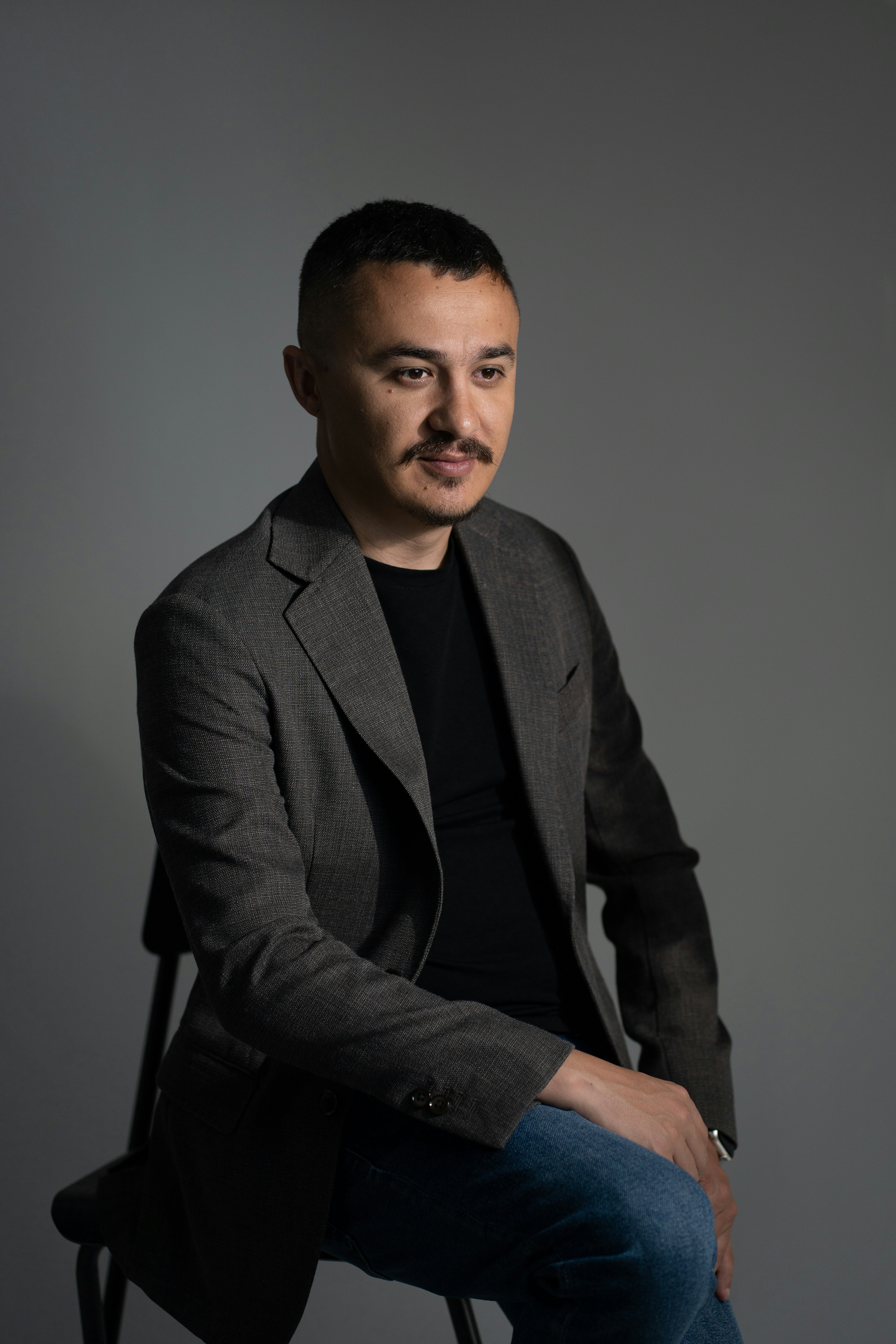A man sits, looking to the side.