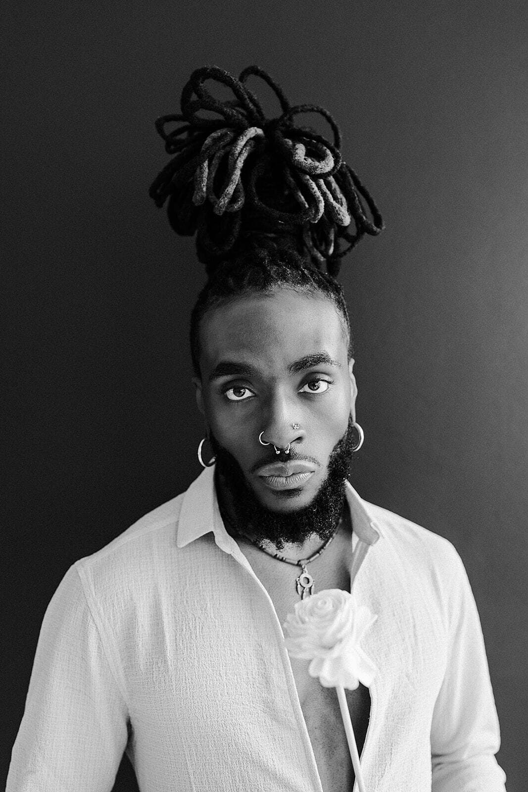  black-and-white portrait of a model with a unique hairstyle and accessories, posing at Revelator Studio in Shreveport, highlighting the studio’s natural light and professional photography space.