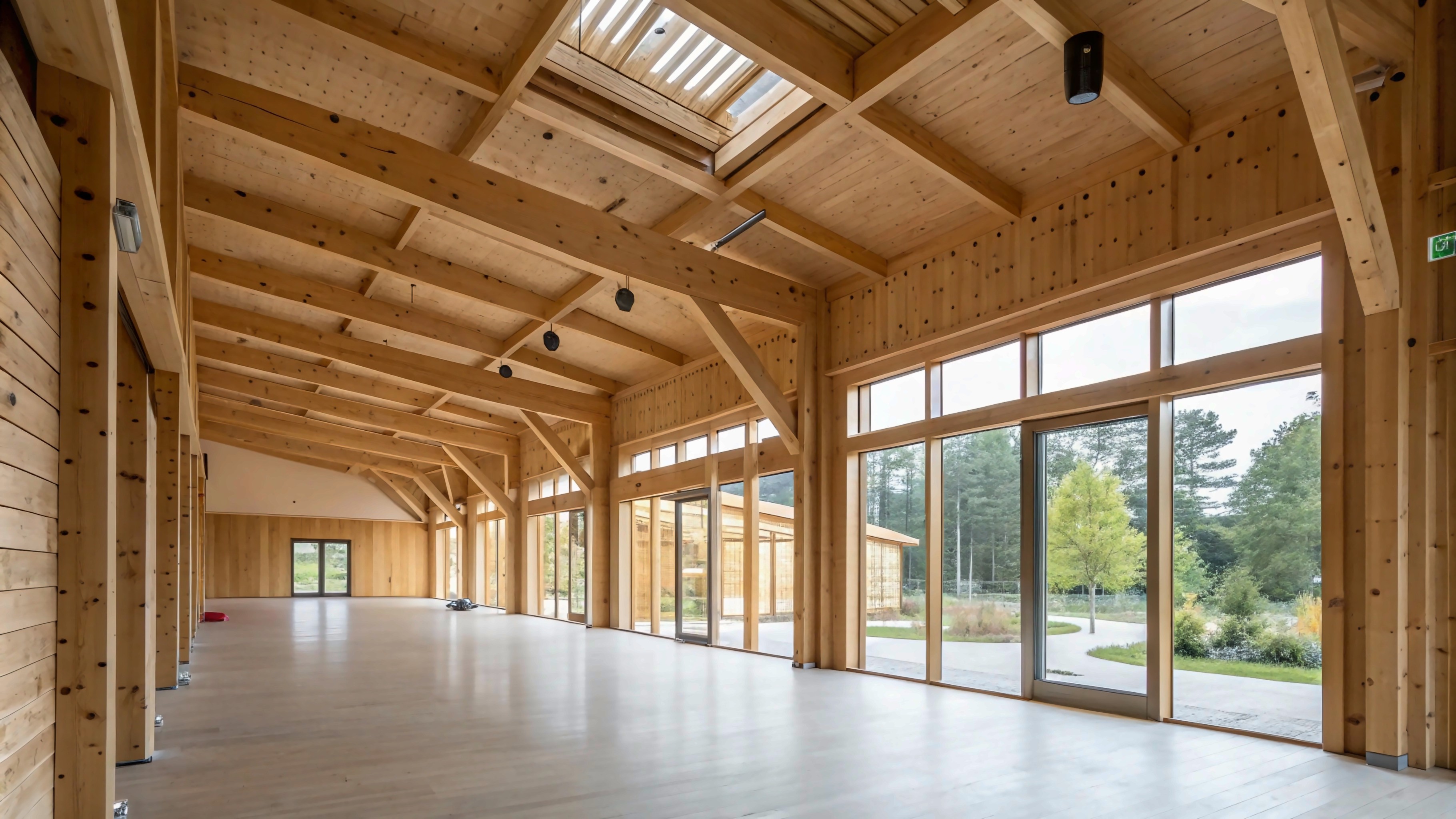 Interior hall with exposed timber ceiling, beams, and full-height glazing.