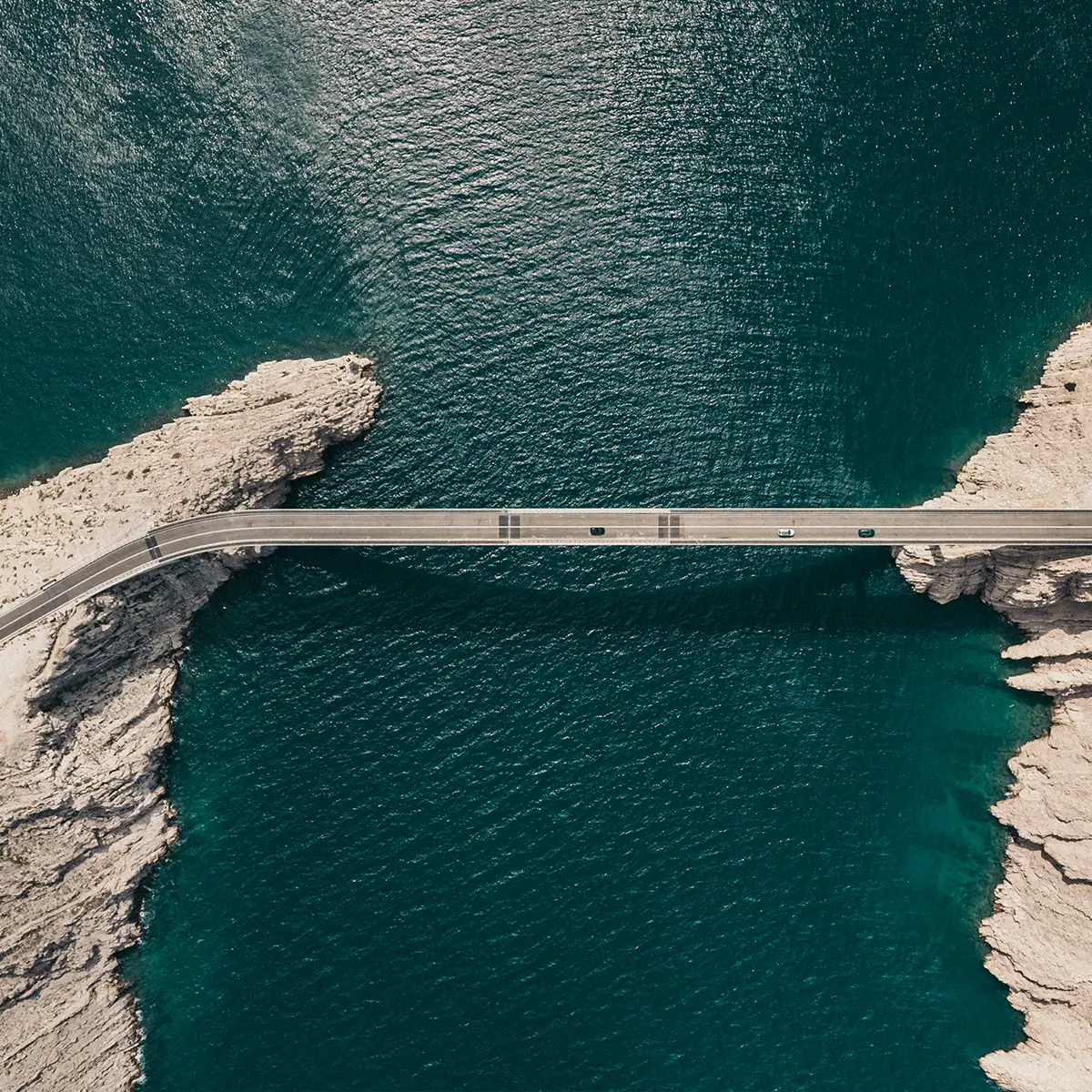 Image of an elevated bridge over a body of water connecting two rocky destinations
