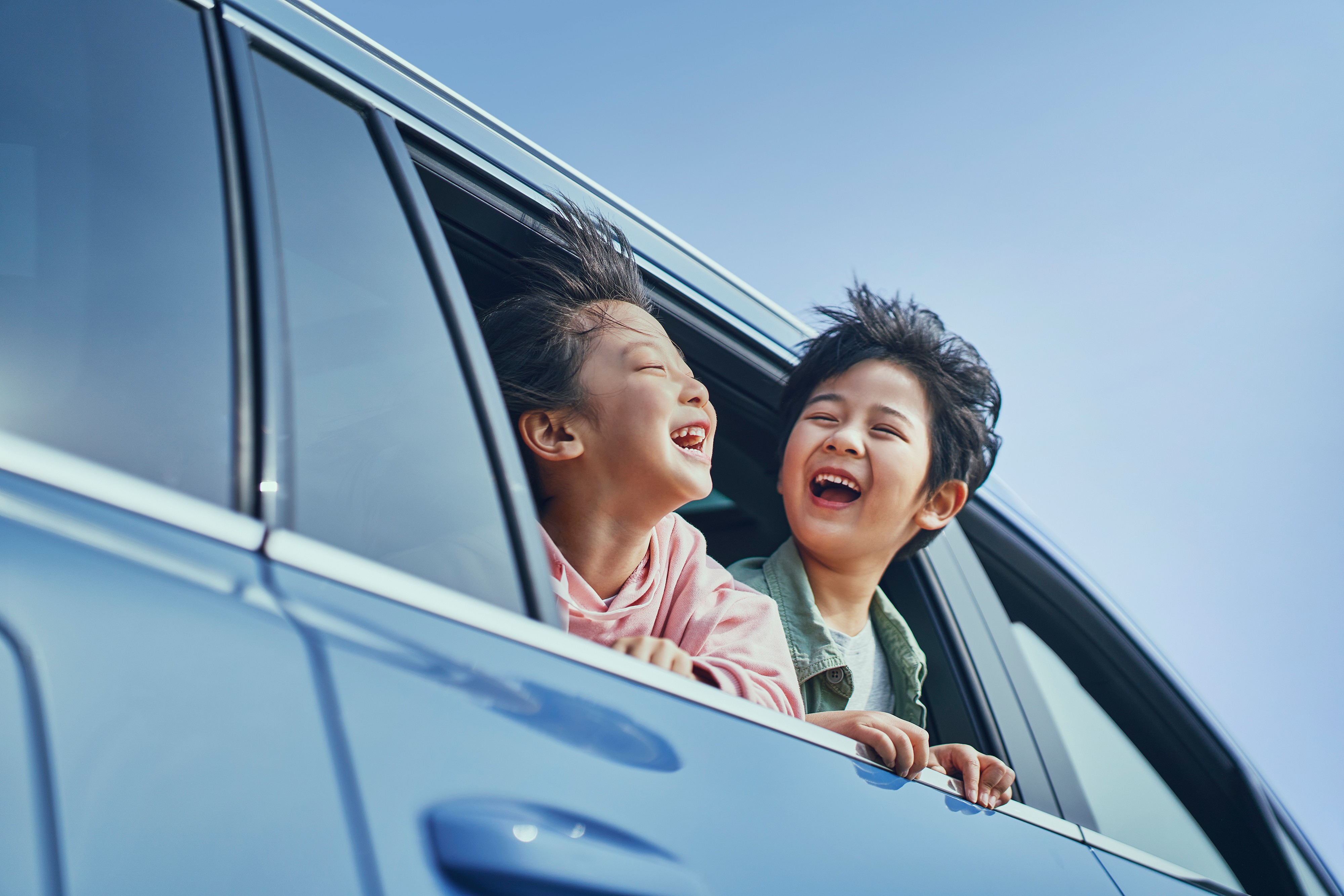 Two cheerful men laughing in the front seats of a sportscar, great for car rental joy promotions.